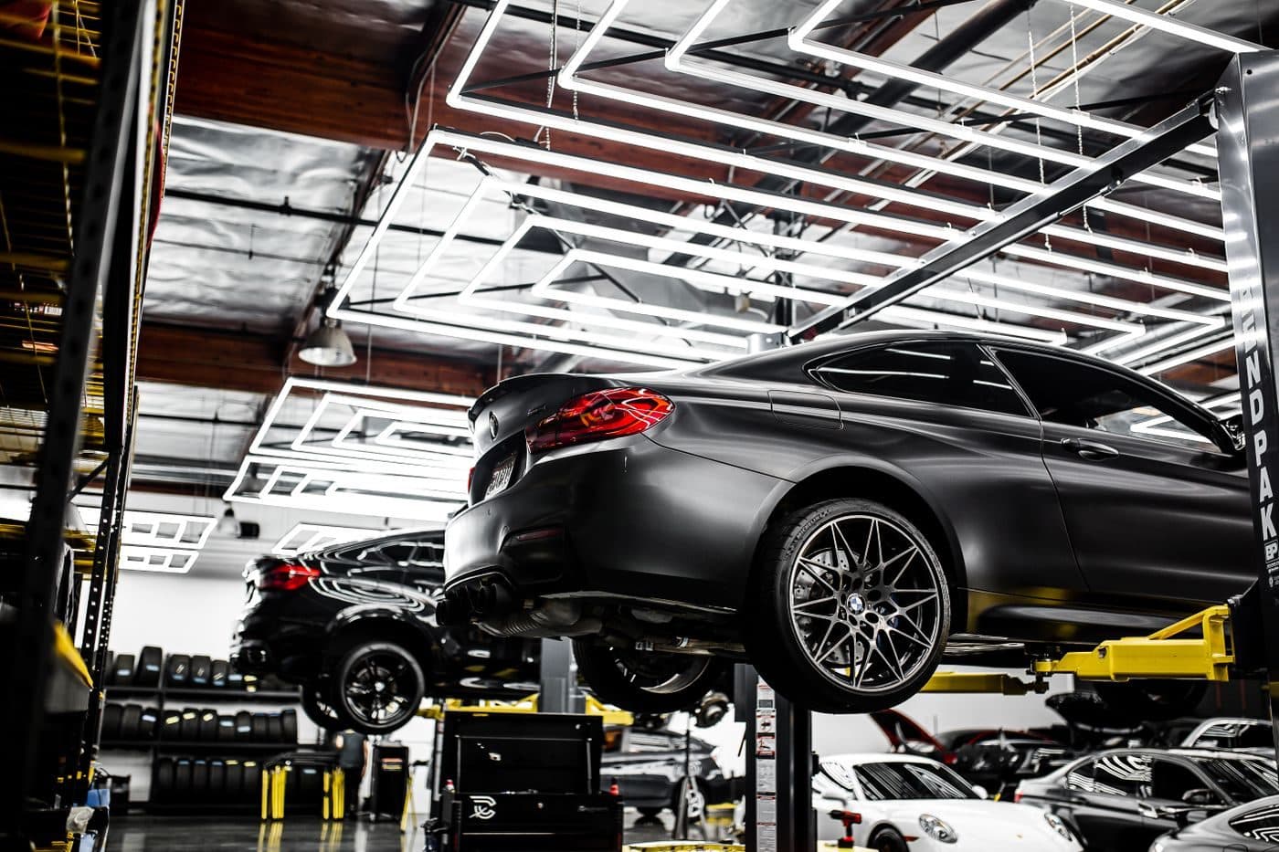 Vehicles raised on two-post lifts in a clean, well-lit workshop